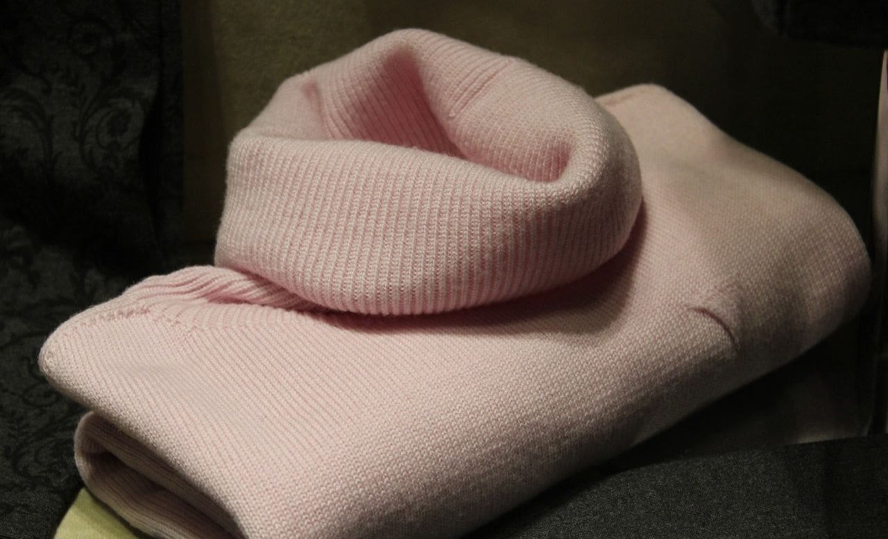 A pink sweater is folded up on the table.